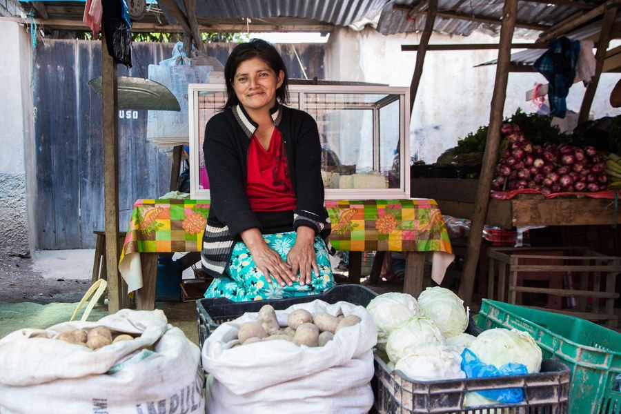 Mujer atendiendo su puesto de frutas y verduras, ejemplo de proyecto local apoyado con una subvención distrital
